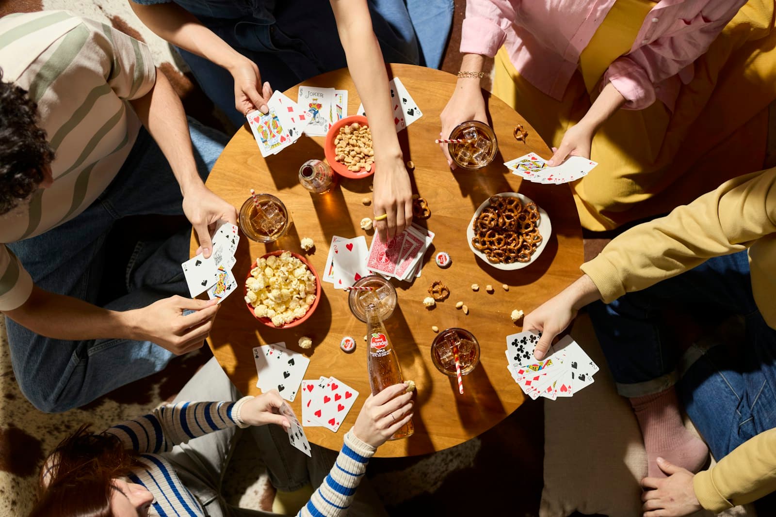 Friends playing cards around a table with snacks