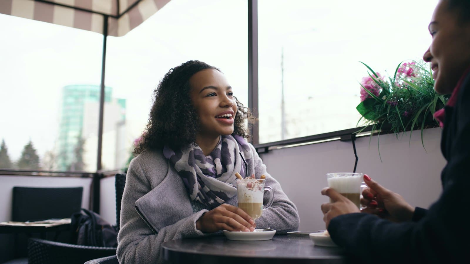 Two people laughing over coffee at an outdoor cafe