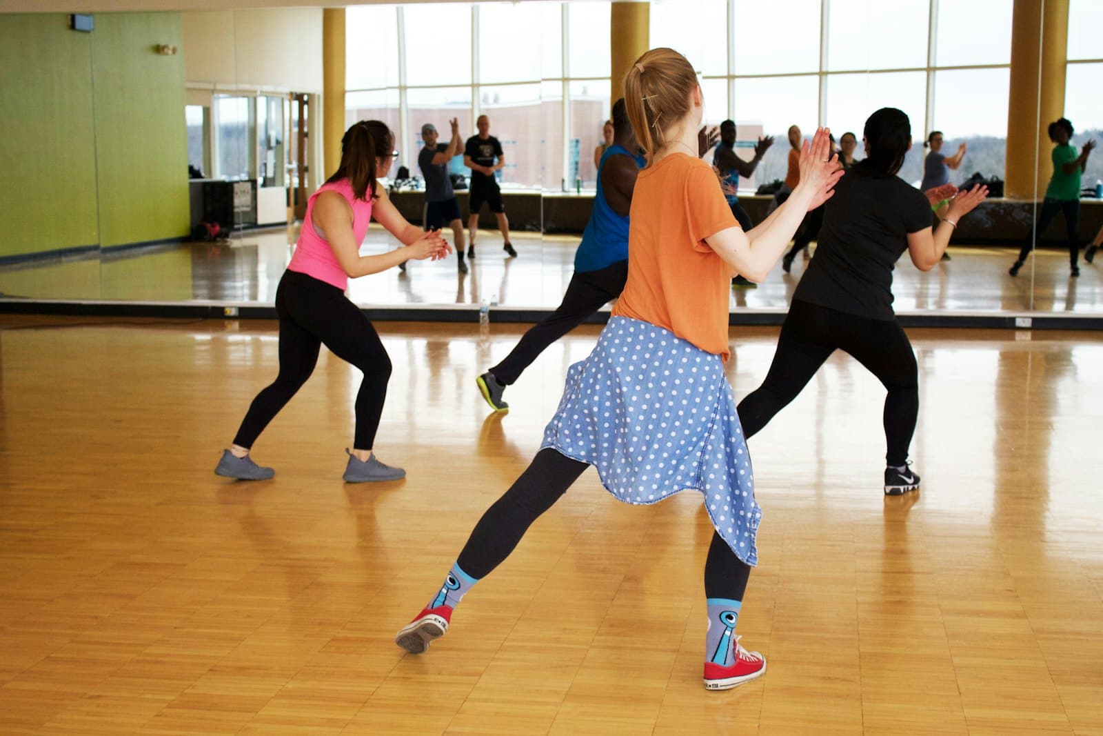 A group dance class mid-move in a bright studio