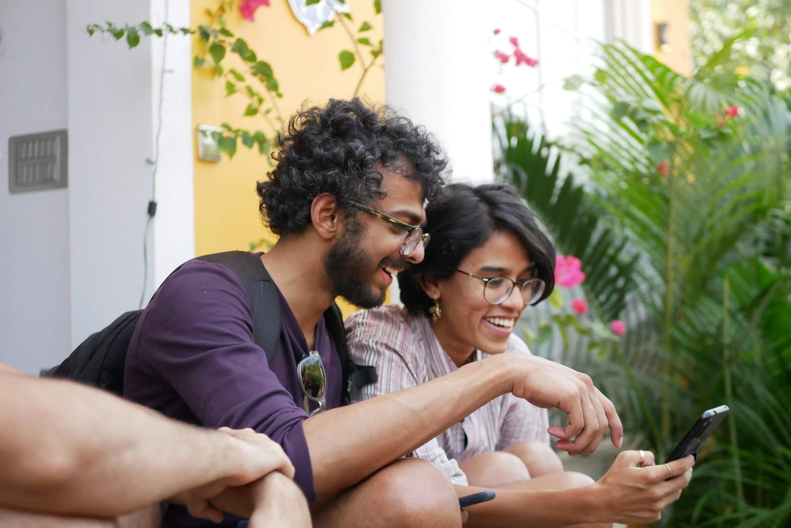 Two friends laughing at a phone outdoors
